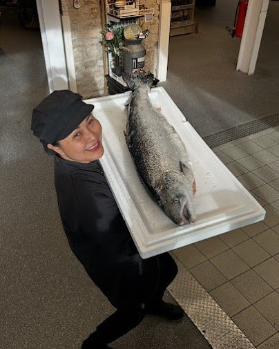 Un membre de l’équipe Sushi des Druides portant un saumon entier fraîchement livré au kiosque